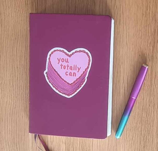my journal no 1, a purple notebook with a heart shaped sticker on the front which says you totally can and pink and green fountain pen.
