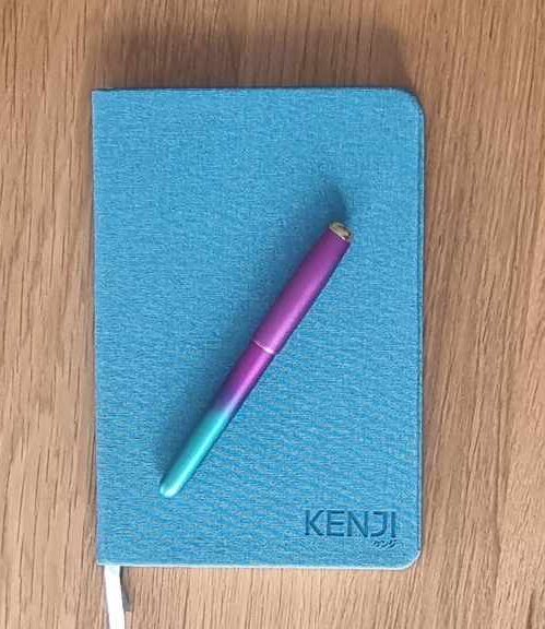 my journal number 2, a blue notebook with Kenji embedded in the cover and a pink and green fountain pen
