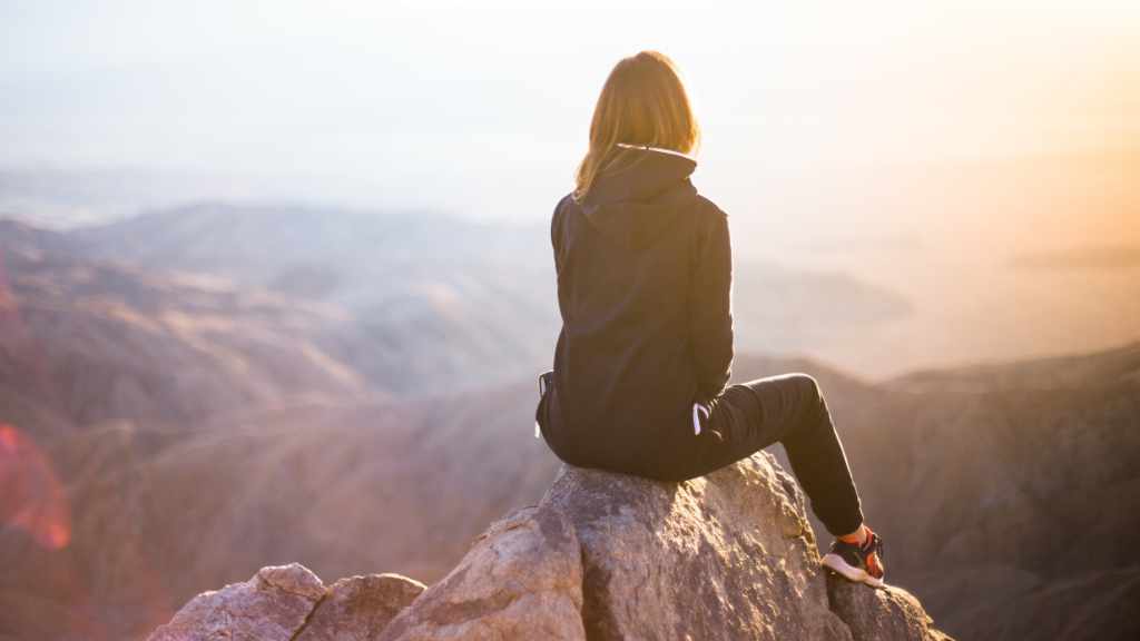 woman sat on top of a rock in part of rocky landscape
