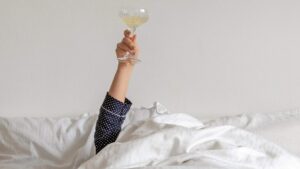 woman in lying in bed holding up a champagne glass
