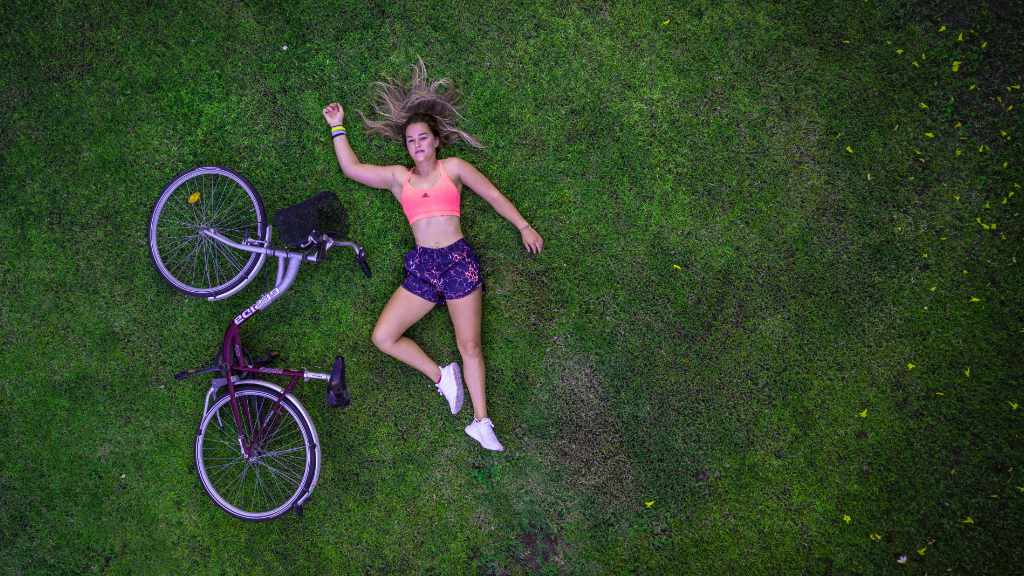 woman lying on her back on some grass with a bike lying down next to her
