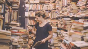 woman in a bookshop which is piled high with books