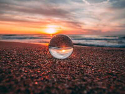 a glass ball on a beach at sunset
