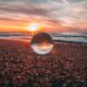 a glass ball on a beach at sunset