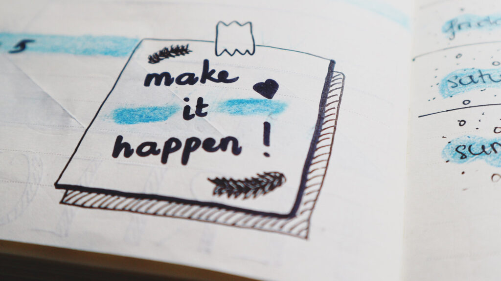 A hand drawn picture in a notebook that says make it happen