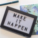 a sign that says make it happen lying on top of a flowery notebook