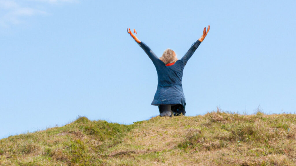 woman at the top of a hill with her arms in the air as she has achieved one of her personal development goals