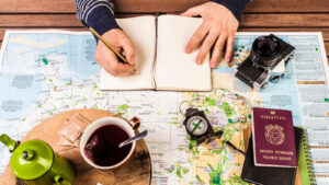 writing a journal while drinking tea with a map, passport and camera